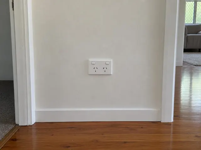 Double power point on a painted interior wall above timber floorboards in Worongary