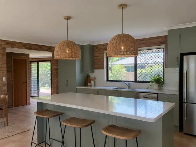 Kitchen island with two woven pendant lights in a brick-walled home in Pacific Pines